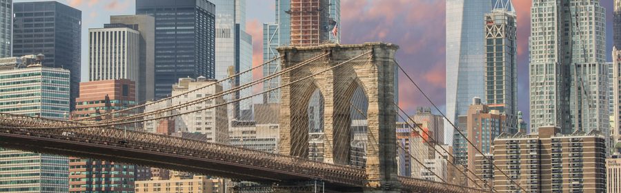 The Brooklyn Bridge with the Lower Manhattan skyline behind it at dusk