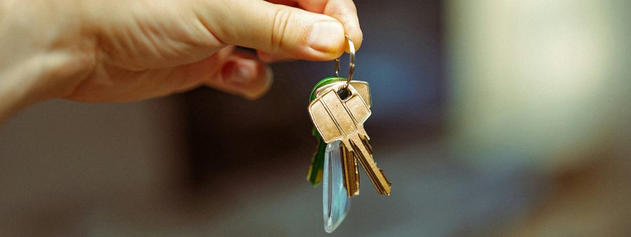 A hand holding out a set of apartment keys